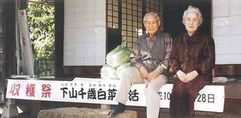 1998年11月28日に開催された第1回復活収穫祭。旧母屋の縁側に座る下山義雄さん・幸子さんのご夫妻。